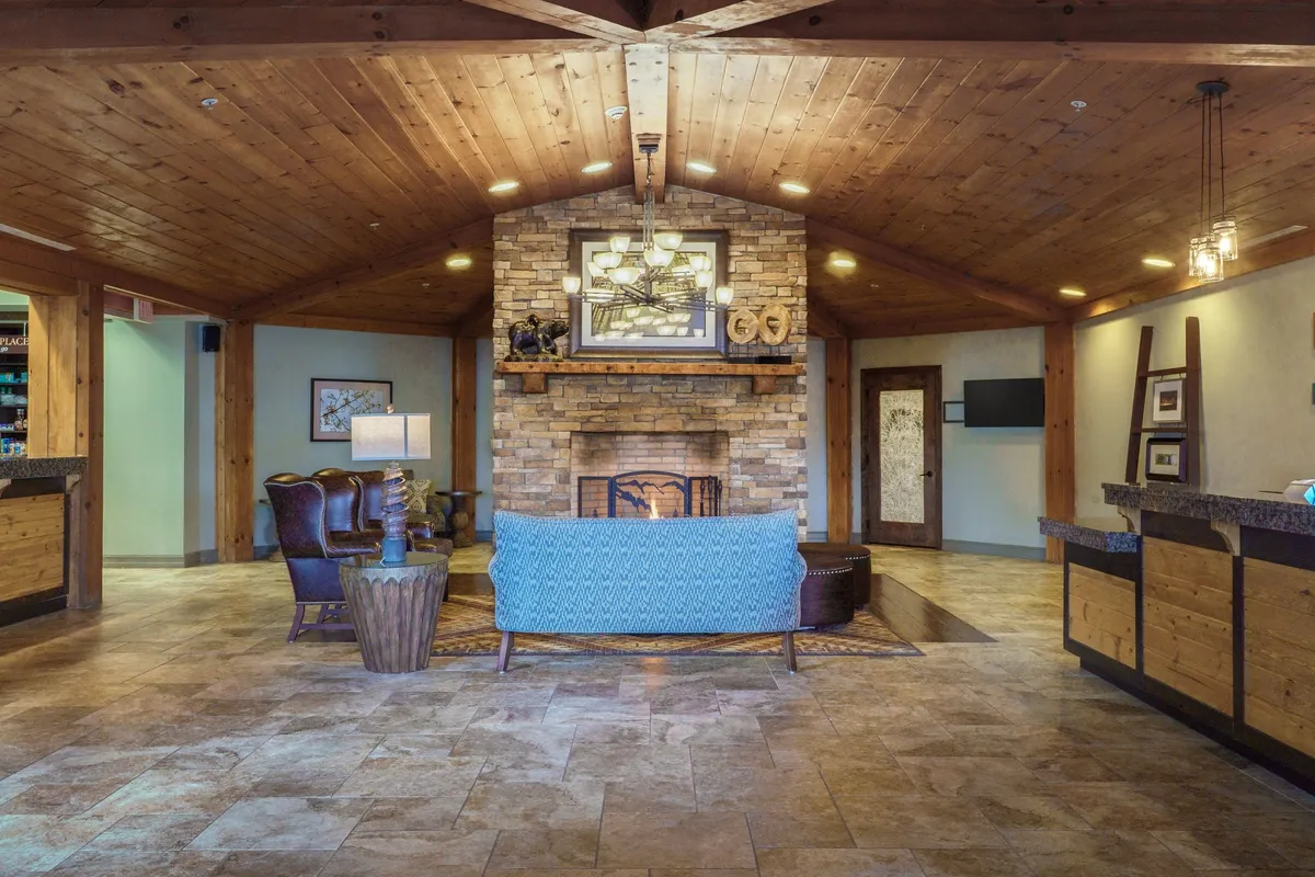A spacious living area anchored by a stone fireplace and a comfortable blue couch, accented by a wooden ceiling. The setting invites families to gather, relax, and socialize in comfort.